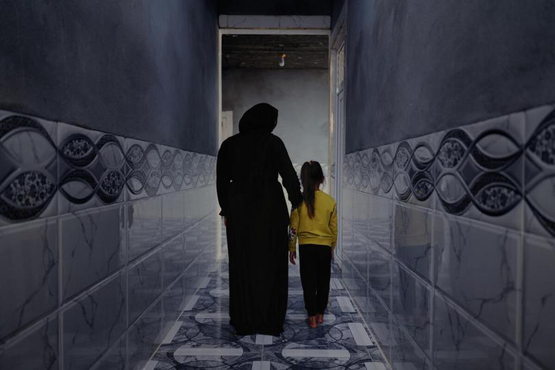 Athaab, 26 walks down the hallway with her daughter Qadar in her home in Sinjar, northern Iraq.